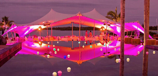 pink lit stretch tent reflection in swimming pool, seating, luxurious